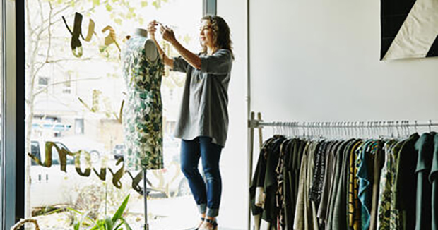 A woman dressing a mannequin in her clothing shop.